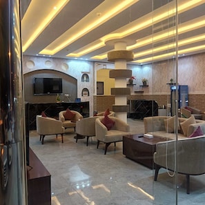Un vestíbulo moderno con televisor, sofás, chimenea y un pilar decorativo.