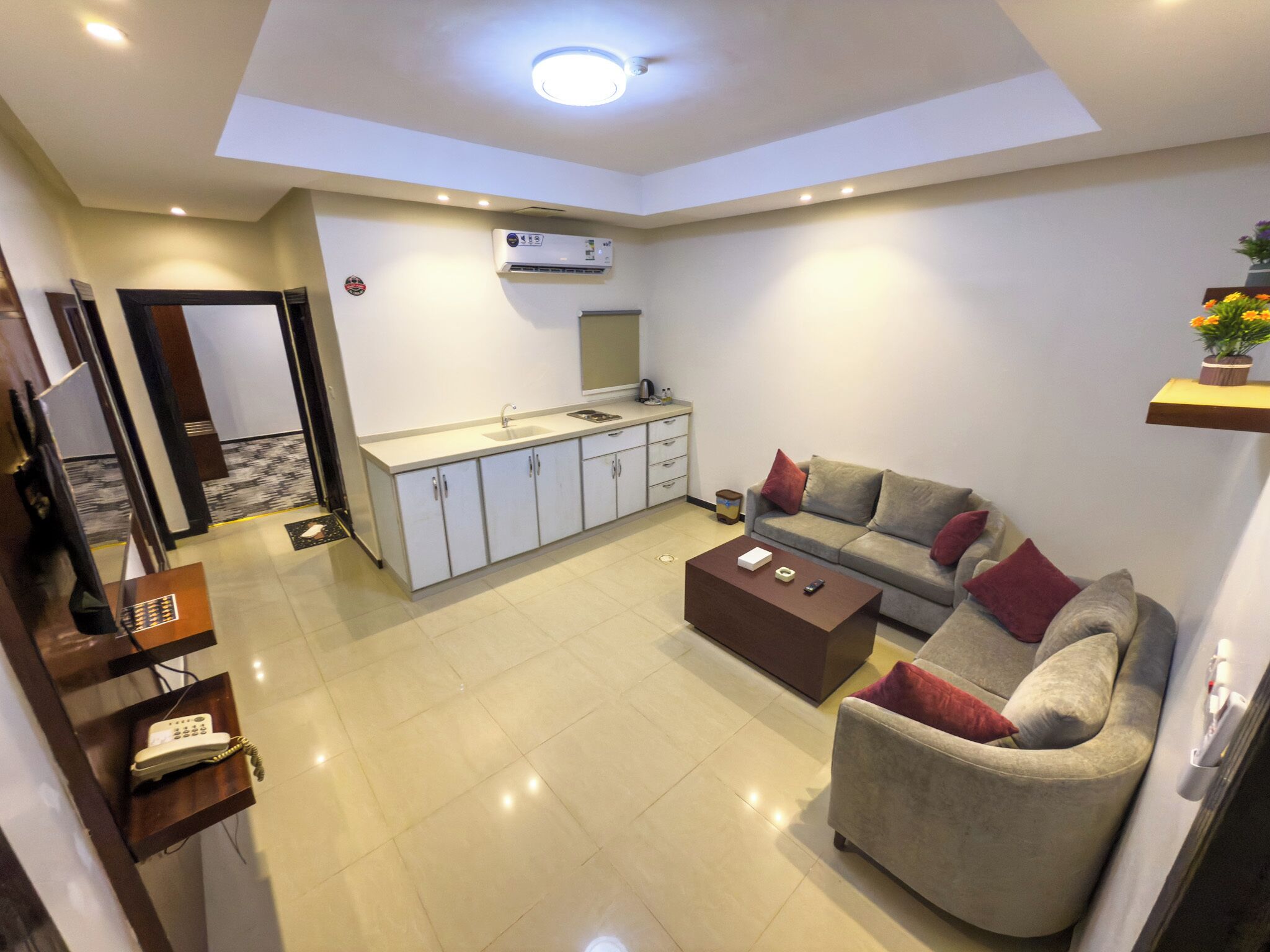 A compact living space with a kitchenette, a sofa, a coffee table, and a small dining area.