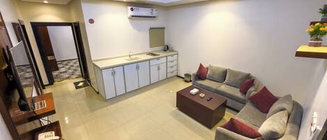 A compact living space with a kitchenette, a sofa, a coffee table, and a small dining area.