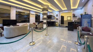 A modern lobby with a reception desk, seating area, and a TV screen. - Lailati Alnahda (Riyadh)