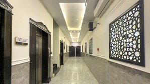 A corridor with marble flooring, black elevator doors, and a decorative wall panel. - Lailati Alnahda (Riyadh)