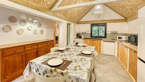 A modern kitchen with wooden cabinets, a dining table set for four, and a view of the outdoors through a window. - Small Creole Kaz with garden and jacuzzi, near Grande Anse beach (Petite-Île)