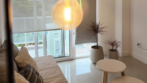 A modern living room with a large window, a sofa, two small tables, and a hanging light fixture. - Esmeralda Apart (Marcos Juárez)