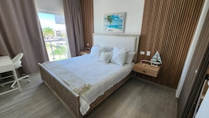Ein modernes Schlafzimmer mit einem großen Bett, einem Schreibtisch und Blick ins Freie.
