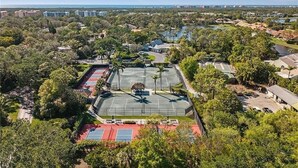 Luchtbeeld van een woongebied met meerdere tennisbanen, omgeven door bomen en gebouwen.