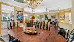 Een ruime eethoek met een houten tafel en stoelen, een kroonluchter en kunstwerken aan de muur.
