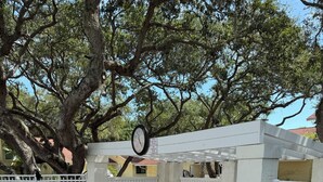 An outdoor patio area with a white pergola, a clock, white plastic chairs, and a table. -  Resort with best location in St. Augustine, FL-2BD/2BA Single Level (St. Augustine)