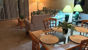 A living room with a glass-top dining table, wicker chairs, a sofa, and two floor lamps. -  Resort with best location in St. Augustine, FL-2BD/2BA Single Level (St. Augustine)