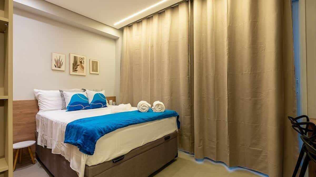 A bedroom with a bed, curtains, a chair, and wall art.