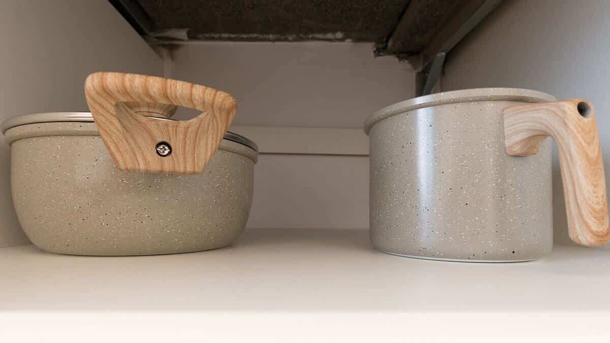 Deux ustensiles de cuisine à manche en bois, posés sur une étagère.