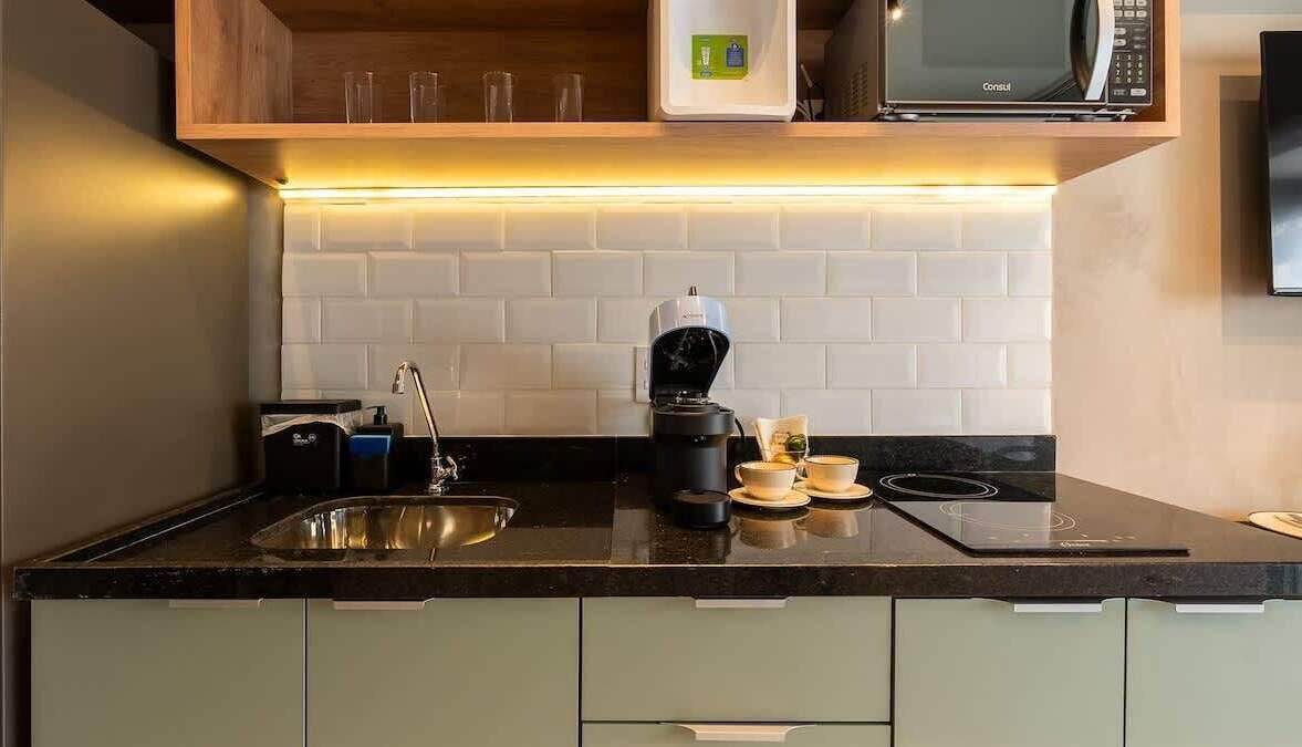 Eine moderne Küche mit integriertem Mikrowellenherd, Kaffeemaschine und einer Spüle aus Edelstahl.