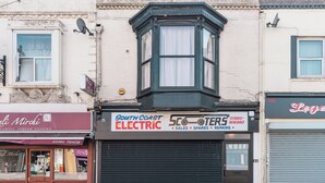 A corner building with a bay window, a closed shuttered shop, and a sign for 'South Coast Electric'. - Cozy 3-Bed Central Southampton (Shirley)