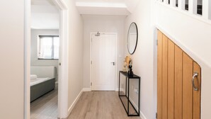 A hallway with a white door, a wooden panel wall, and a black-framed mirror. - Cozy 3-Bed Central Southampton (Shirley)