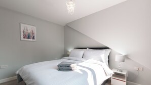 A modern bedroom with a bed, bedside table, and a chandelier. - Cozy 3-Bed Central Southampton (Shirley)