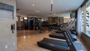 Un gimnasio moderno con cintas de correr, máquinas de pesas y un espejo grande.