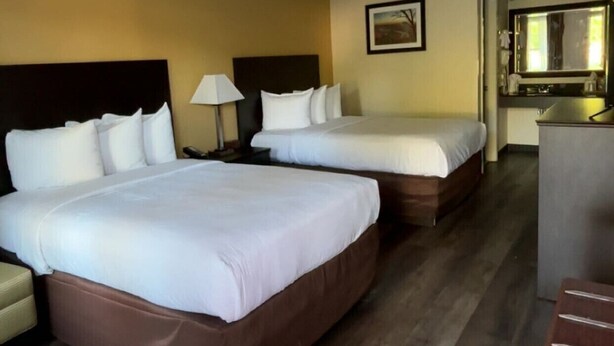 A hotel room with two beds, a desk, a chair, and a kitchenette. - Arab Knights Inn (Arab)