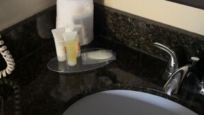 A bathroom with a black marble sink, a towel dispenser, and toiletries on a tray. - Arab Knights Inn (Arab)