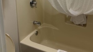 A bathroom with a bathtub, toilet, and a shower curtain. - Arab Knights Inn (Arab)