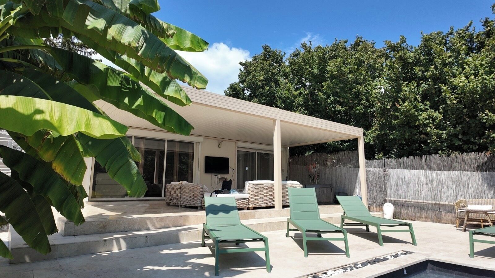 Un espace extérieur abrité comprenant une piscine, des chaises longues et un téléviseur.