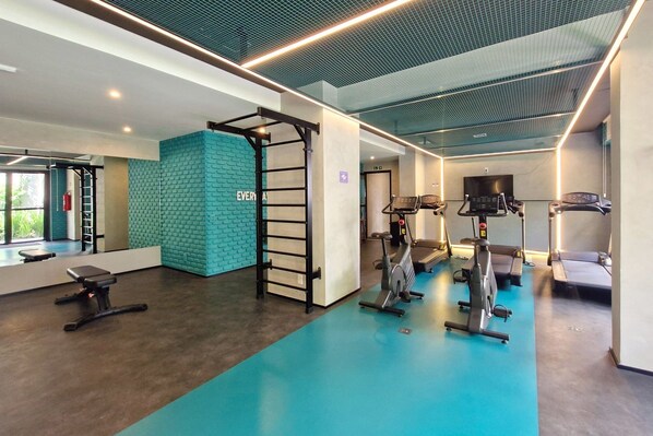 A modern gym with exercise equipment, a pull-up bar, and a blue wall.