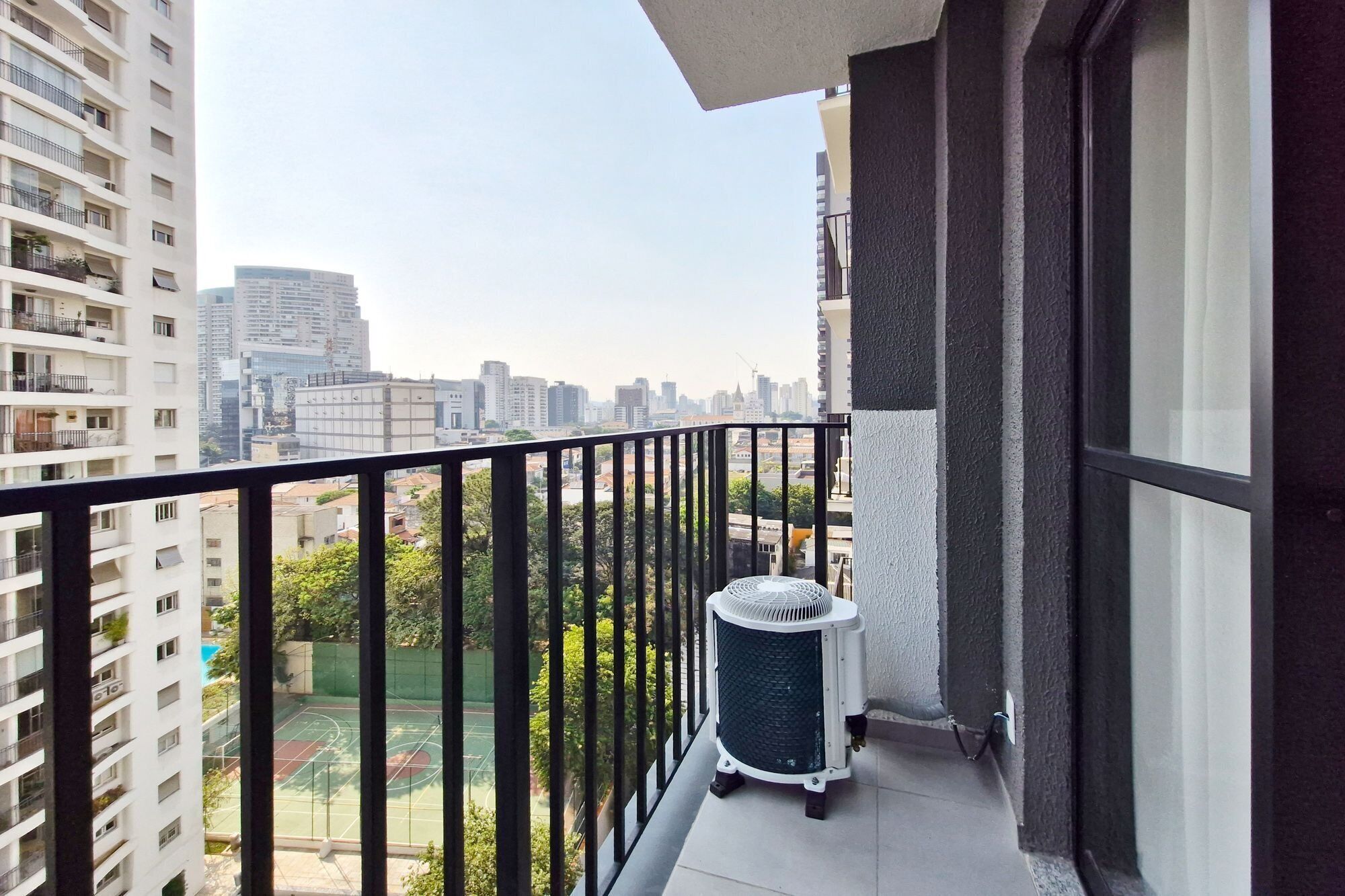 Ein Balkon mit Blick auf eine Stadtlandschaft, ein weißer Terrassenheizer und ein Mülleimer.