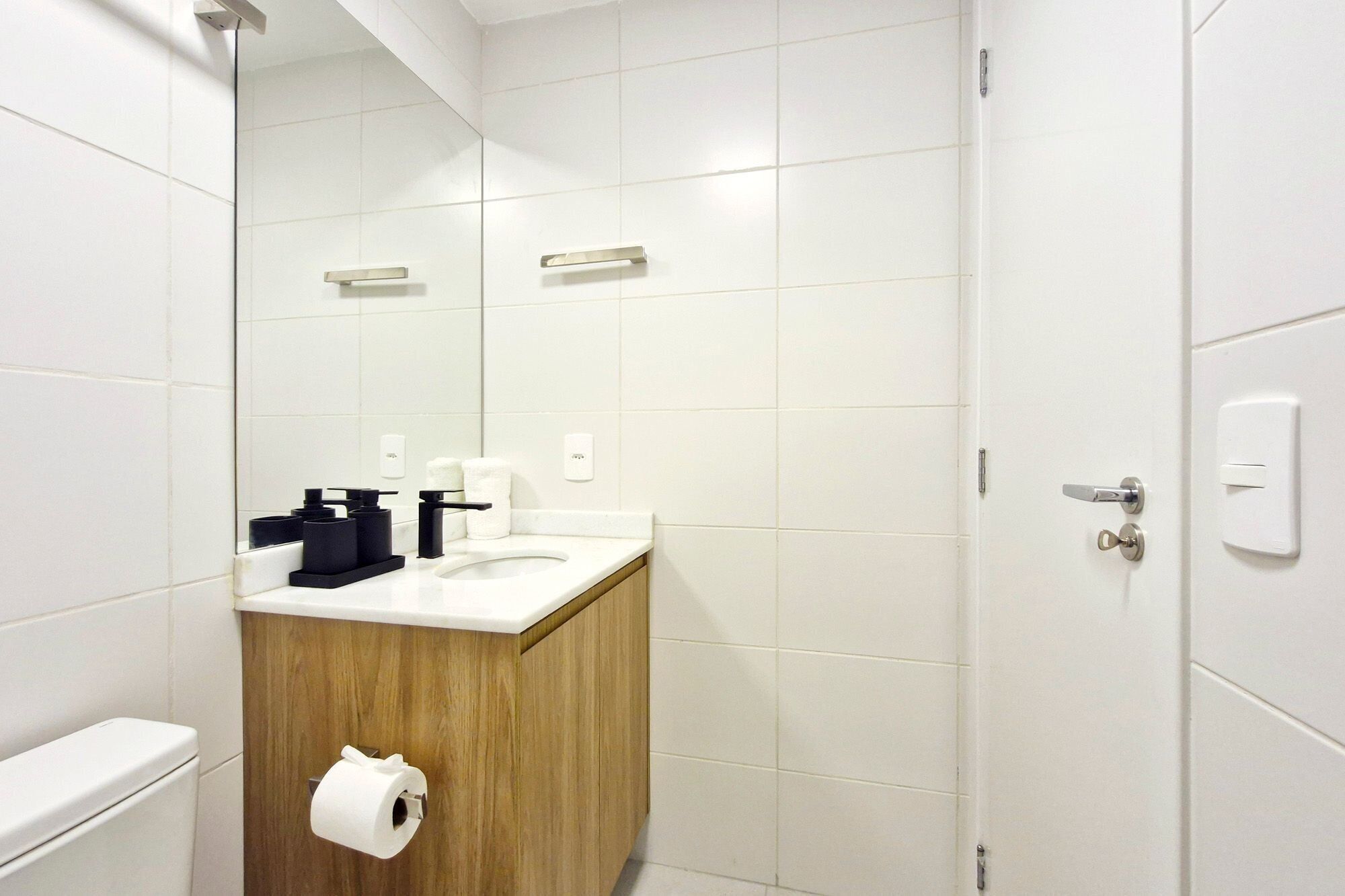Une salle de bain moderne avec un lavabo blanc, un meuble-lavabo en bois et un miroir.