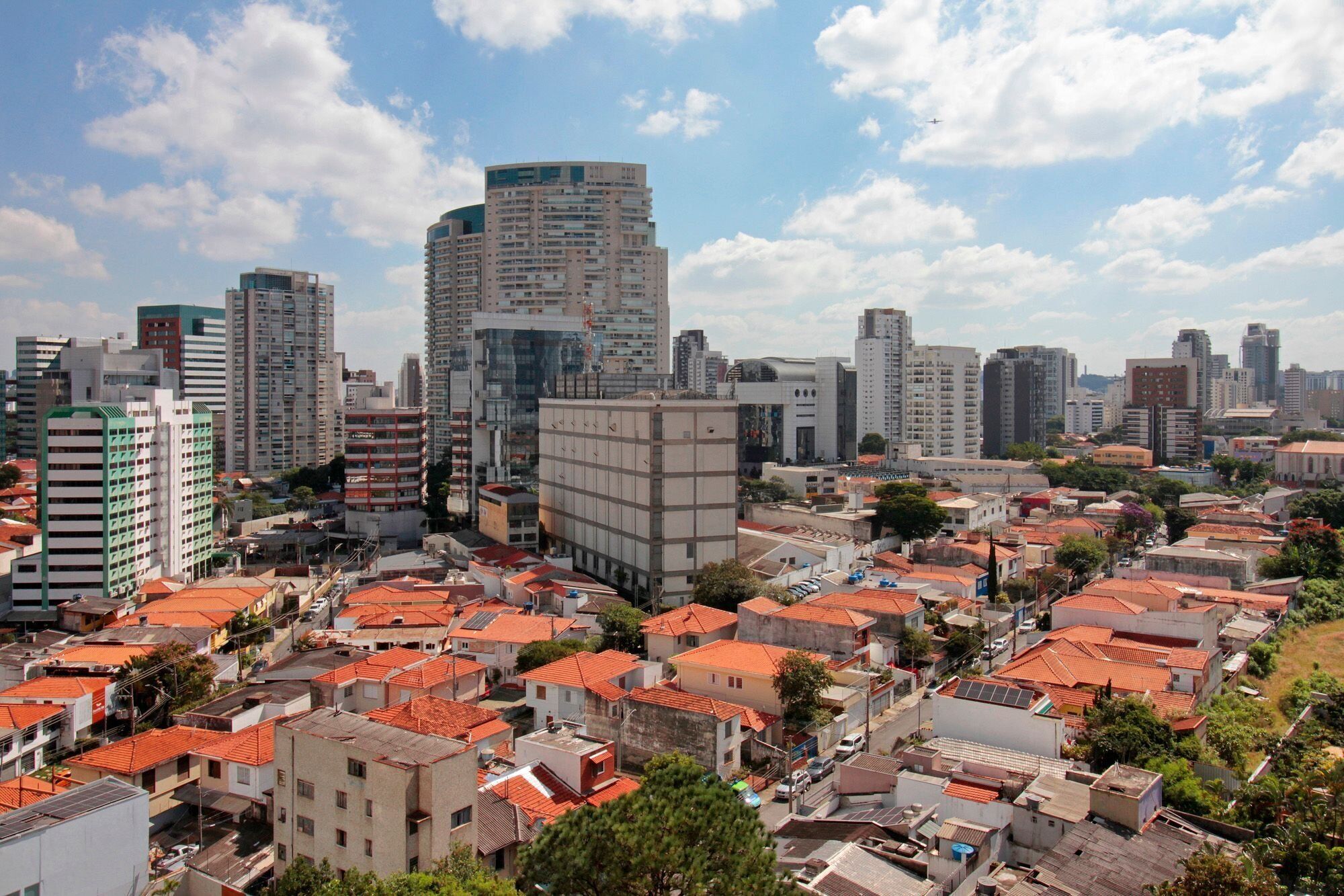 A cityscape with high-rise buildings and residential areas with red-tiled roofs.