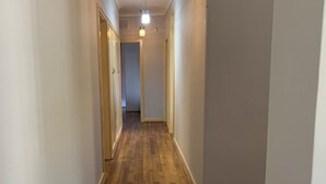 Kapea käytävä, jossa on puulattia ja valkoiset seinät.
