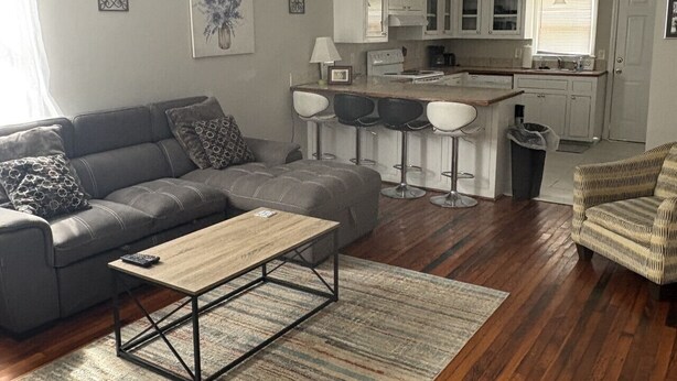 Una sala de estar moderna con un sofá gris, una mesa de centro de madera y una alfombra estampada.