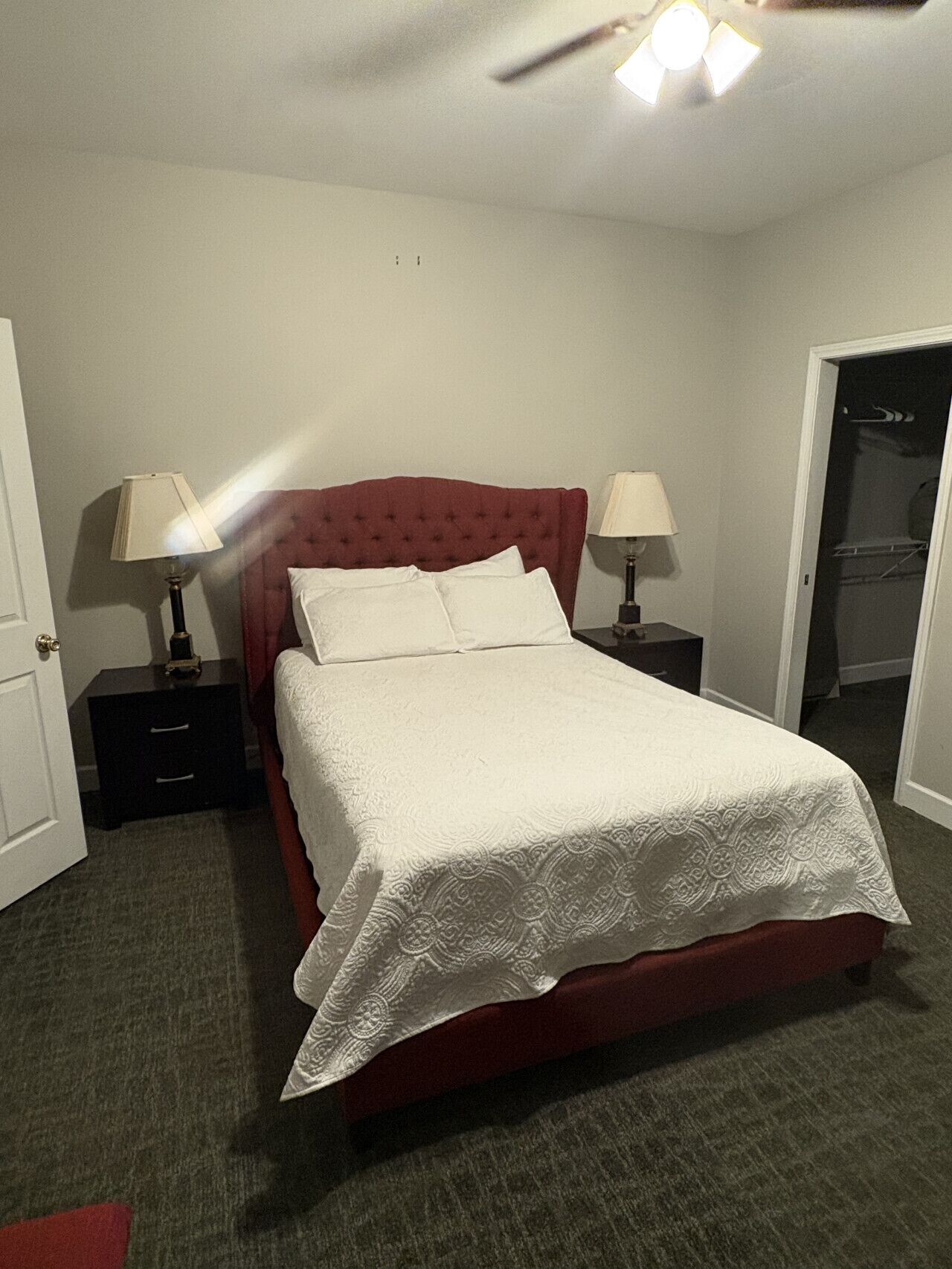Een standaard hotelkamer met een enkel bed, twee nachtkastjes met lampen, een kledingkast en een plafondventilator.