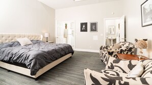 A bedroom with a large bed, a patterned sofa, a bedside table, and a mirror. - Sky cottage near downtown (Columbus)