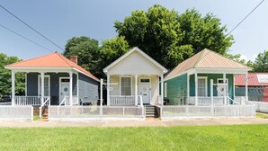 Three small, single-story houses with white picket fences, each with a distinct color: blue, white, and green. - Sky cottage near downtown (Columbus)