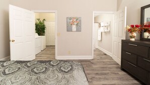 A bedroom with a bed, a dresser, a mirror, and a hallway leading to a bathroom. - Apple cottage near downtown (Columbus)