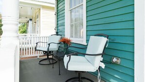 A porch with two white chairs and a table, a white railing, and a window with a white frame. - Apple cottage near downtown (Columbus)