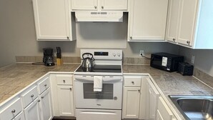 A kitchen with white cabinets, a stainless steel sink, a double oven, and a coffee maker.
