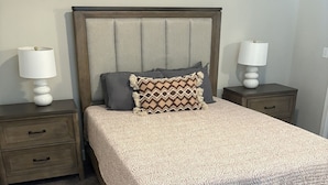 A bedroom with a bed, two nightstands, and two lamps.