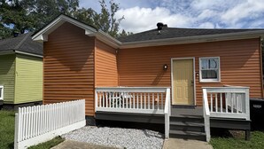 A single-story house with a front porch, a door, and a small window. - Oak Bungalow in Midtown (Columbus)
