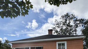 A single-story house with a front porch, a white picket fence, and a clear sky. - Oak Bungalow in Midtown (Columbus)