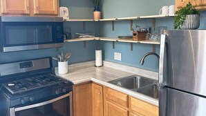 A kitchen with wooden cabinets, a stainless steel refrigerator, a microwave, a stove, and a sink. - Boutique Studio Apartment (La Porte)
