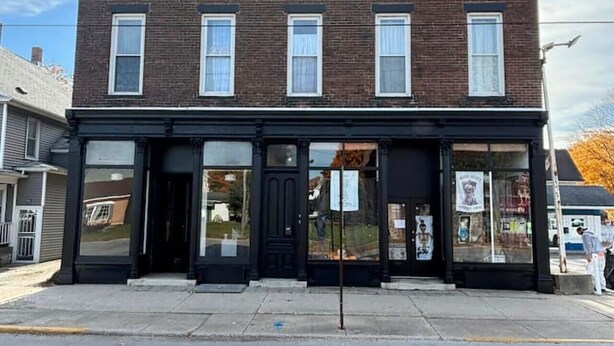 A two-story brick building with a black storefront and large windows.