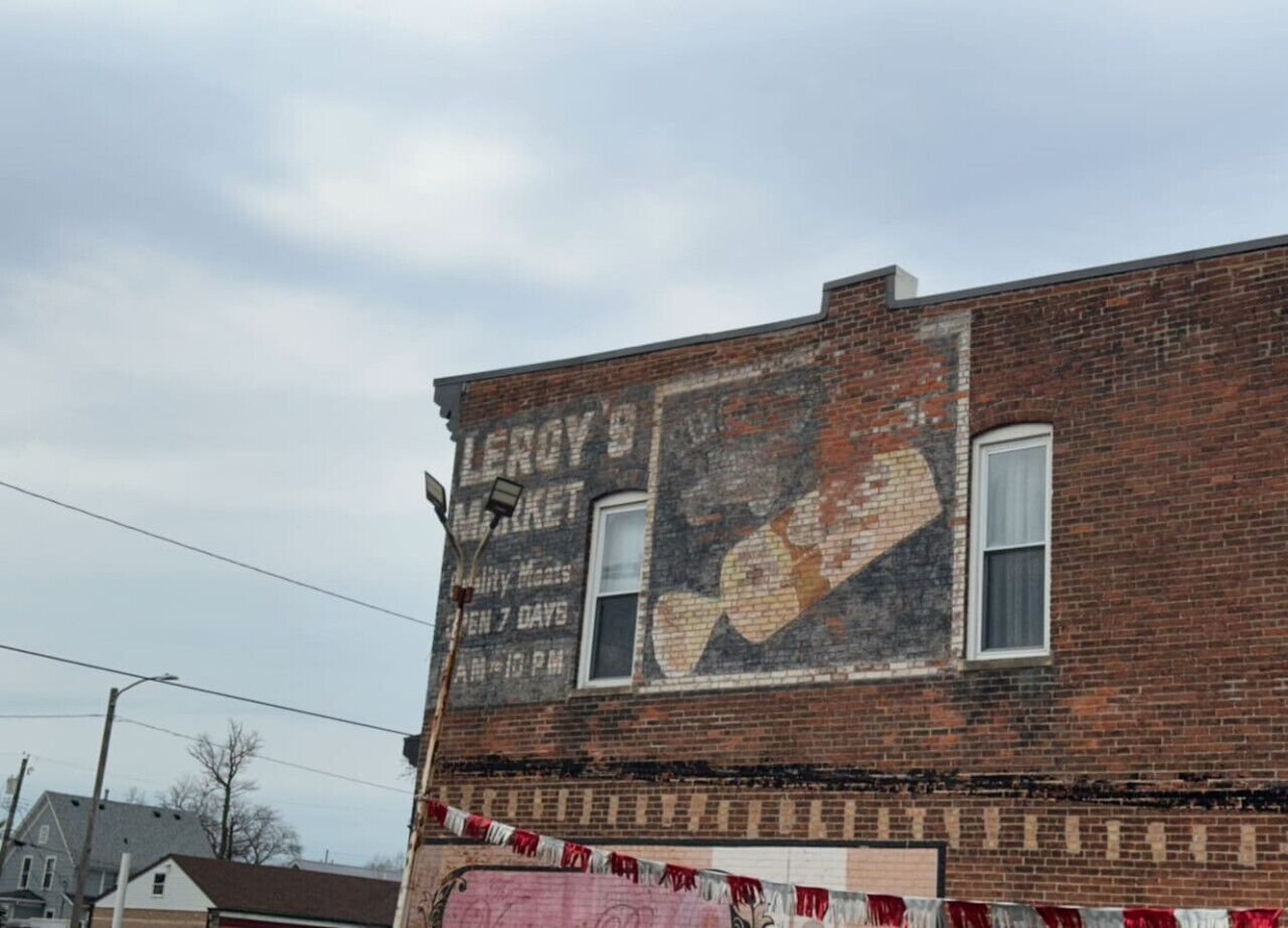 En murstensbygning med et falmet mural, der reklamerer for Leroy's Market.