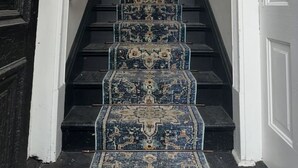 A staircase with a patterned carpet leading to a room.