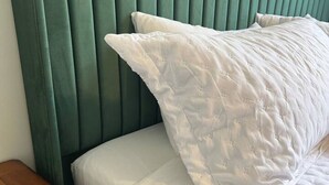 A bed with a green upholstered headboard and white bedding.