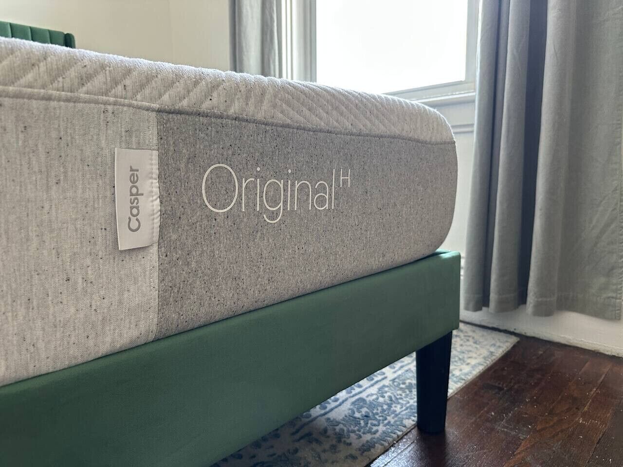 Een matras met de aanduiding 'Original' op een groen bedframe.