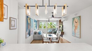 A modern dining area with a white table and chairs, a ceiling fan, and pendant lights. - Charming Beachfront Retreat - Wake Up to Waves - 2 BD Apt with AC at Río Grande (Río Grande)