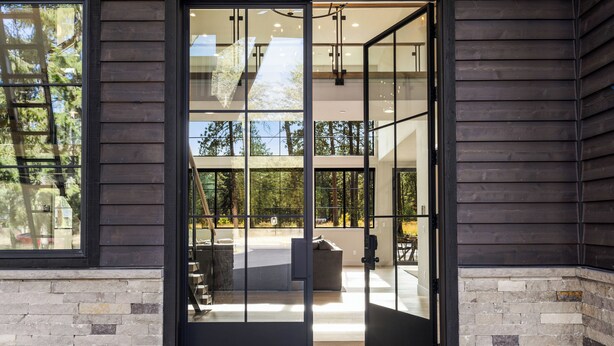 A modern building entrance with a glass door, stone walls, and a view of the outdoors. - Lakefront Resort Home w/ Private Pool, Hot Tub & Fire Pit - Sleeps 14 (Cle Elum)