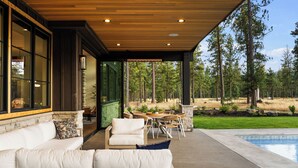 A covered outdoor seating area with a pool, wooden ceiling, and large windows overlooking a forest. - Lakefront Resort Home w/ Private Pool, Hot Tub & Fire Pit - Sleeps 14 (Cle Elum)