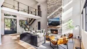 Ein geräumiges Wohnzimmer mit modernem Kamin, einer Treppe und einem großen Fenster mit Blick auf eine Stadtlandschaft.