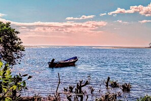 A boat on calm water with a clear sky and distant land. - Poneloya Budget Rooms  (Leon)