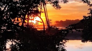 A sunset over a body of water with trees framing the view. - Poneloya Budget Rooms (Leon)